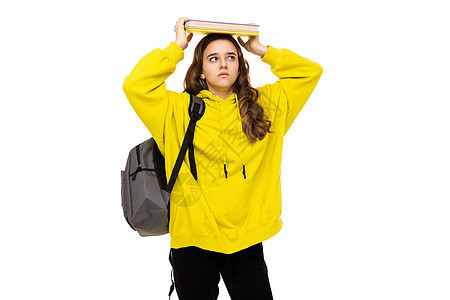 一个美丽的黑发少女穿着时尚的黄色运动连帽衫 背着灰色背包 拿着很多书来学习 她的头被白色背景隔离 有可用的文本空间 办学理念图片