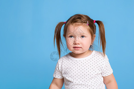 一个可爱的小女孩 带着猪尾巴笑在蓝色孤立的背景上 为了幸福或童年的概念而微笑图片