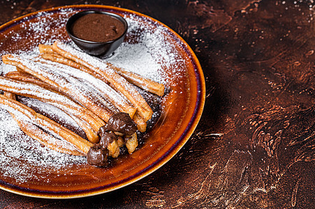 含糖和巧克力酱的西班牙塔帕斯 churros 暗底背景 顶视图 复制空间图片