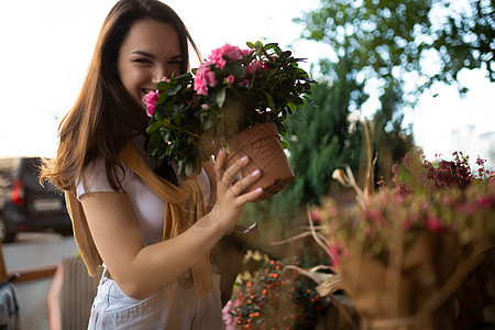 美丽的年轻黑发美女 在花店的门廊上享受花盆中的鲜花顾客红色市场女士购物植物礼物商业玫瑰花束图片