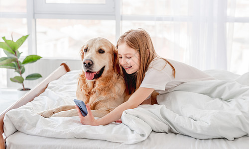 配有金色寻金犬和智能手机的女孩友谊女性动物童年细胞朋友宠物伴侣微笑拥抱图片