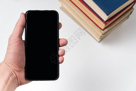 手机在手在书籍的背景上 电子书的概念 白色背景复制空间图片