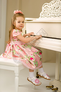 美丽的小女孩在用白色大钢琴弹琴爱好乐器女孩钢琴家演员剧院钥匙旋律和弦教育图片