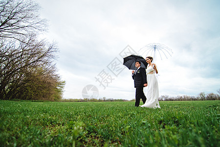 新娘和新郎在雨季的结婚日散步白色下雨黑色新婚喜悦女孩绿色夫妇天气裙子图片