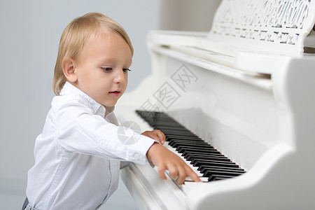 画室里的小孩 在白色钢琴附近歌曲教育男生幼儿园学习微笑学校乐趣音乐钢琴家图片