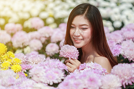 在菊花发光园中的美丽女子女性微笑花园花店头发成人园丁女孩阳光公园图片