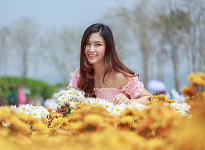 在菊花发光园中的美丽女子女孩公园微笑阳光头发女性幸福成人园丁花店图片