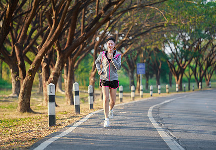 在公园中运行的健身妇女赛跑者训练女性女士娱乐成人树木慢跑者运动活动图片