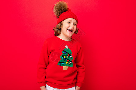 有卷卷卷卷的酷男孩 红色背景 穿着毛衣和圣诞树新年情绪销售卷发行动背景图片