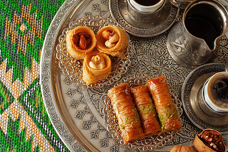 传统的阿拉伯甜甜点肉汁 加一杯咖啡土豆咖啡糖浆午餐软糖面团金属蜂蜜烹饪蛋糕糕点面包图片