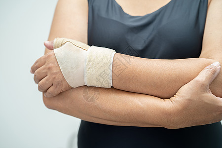 亚洲中年妇女用弹性绷带亲手和手指在办公室治疗德克韦因综合症 20成人电脑手腕笔记本治愈商务键盘商业肌肉手臂图片