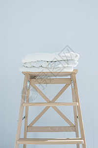 一堆干净的浴巾 彩色棉质特里纺织品堆放在木椅上 靠近白墙桩概念特写纺织品折叠棉布身体卫生桌子织物洗衣店温泉毛巾图片