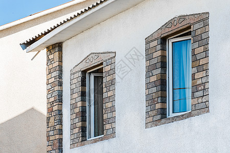 房屋外墙的部分现代内地 有白石膏墙和双层玻璃窗上装饰的石头形状;在两层窗户上图片