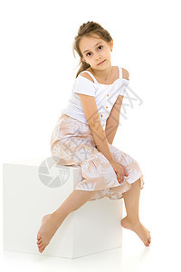白立方体上深思熟虑美丽女孩的肖像裙子衬衫女孩衣服童年太阳裙青春期孩子头发沉思图片