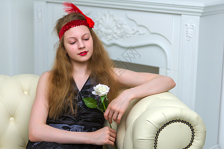 女孩坐在沙发上 手里拿着一朵花花束女性头发工作室休息裙子魅力房间微笑喜悦图片