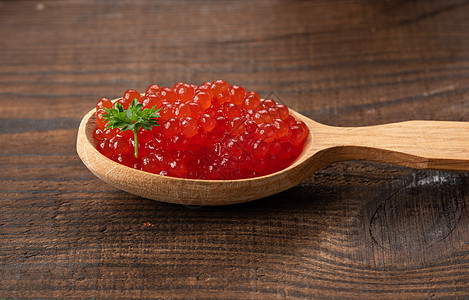 粉红鲑鱼的红色鱼子酱 躺在棕色木桌上的木勺子里图片