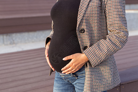 积极的怀孕概念 年轻企业或学生孕妇腹部的特写镜头 未来的妈妈在怀孕后期工作或学习图片