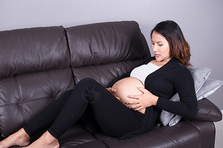 孕妇在起居室收缩的怀孕妇女母性肚子压力母亲房子女性腹部家庭成人长椅图片