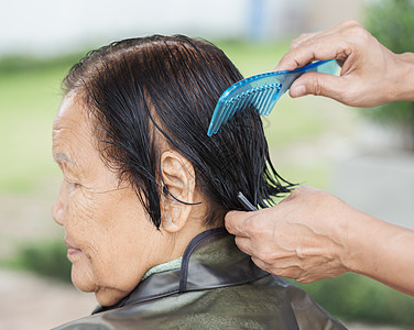 用手梳梳子来理理一位年长妇女的头发图片