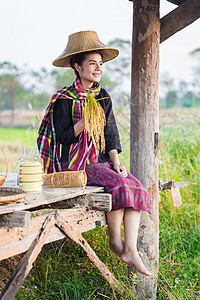 拥有大米和坐在稻田小屋的农民妇女收成文化女士帽子微笑腰布劳动农村女性农业图片