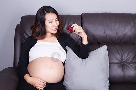 孕妇在沙发上在家用红苹果休息家庭房间饮食食物肚子妈妈婴儿女性微笑成人图片