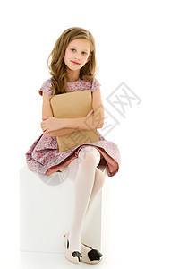 美丽的女孩坐在白色立方体和拥抱书上图片