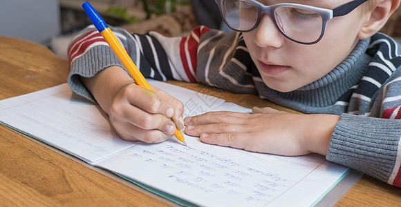 重点突出的一年级学生学习写作和做功课学校女孩班级桌子铅笔彩色男生眼镜童年家庭作业图片