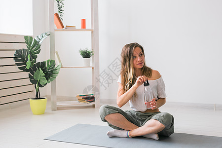 年轻美丽的女孩在垫子上练瑜伽 休息时喝着饮用水 健康 健康的生活方式概念运动装动机运动女性房间力量运动员有氧运动瓶子培训师图片