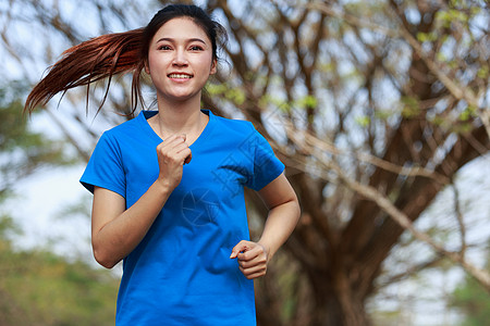 在公园中运行的美丽健身女子训练树木女孩赛跑者女士运动成人娱乐蓝色活动图片