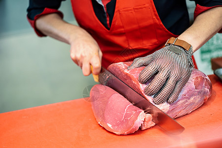 妇女用金属安全网手套在一家屠宰店里切鲜肉火腿牛肉女孩屠宰场市场商业杂货店工作白色食物图片