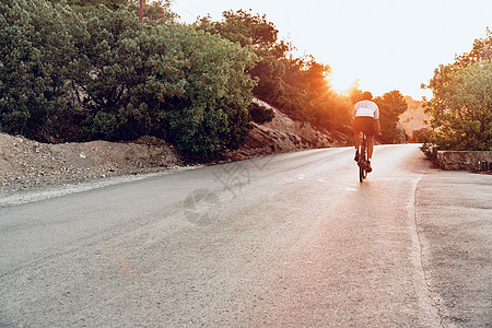 骑单车者在日落的野外公路自行车上行驶骑士运动员太阳镜肌肉头盔行动运动男人速度男性图片