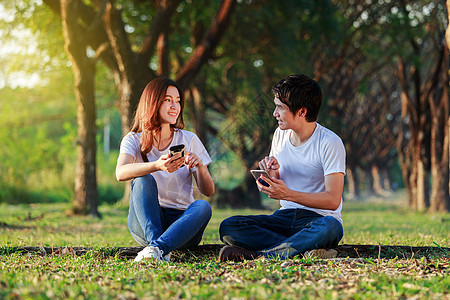 夫妇使用移动电话和在公园中交谈友谊手机女士女朋友男朋友男人乐趣女性朋友们夫妻图片