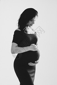 怀着肚子的美丽的年轻怀孕少女在工作室里摆出黑白照片和黑白相片 孕妇和母亲幸福父母母性女孩药品女士生育力妈妈女性腹部拥抱图片