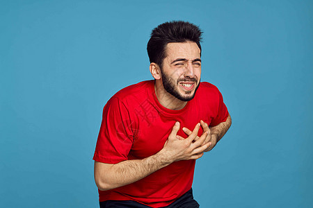 男性穿红色T恤男子的健康问题 情绪症状蓝色背景心脏病学卫生男人呼吸心血管逮捕胸部药品手臂失败图片