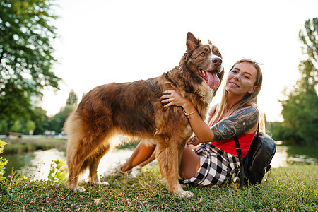 年轻美女在公园宠爱可爱的狗拥抱女士朋友微笑友谊犬类喜悦动物乐趣女孩图片