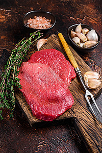 屠宰木板上的肉肉牛排 深底背景 顶层风景烧烤香料牛肉鱼片屠夫胡椒食物牛扒草本植物砧板图片