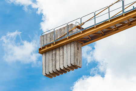 在一座高塔起重机的尾部对着蓝色天空的工业设备上 加添水泥块运输金属抗衡建造工地城市项目水泥建筑建筑学图片
