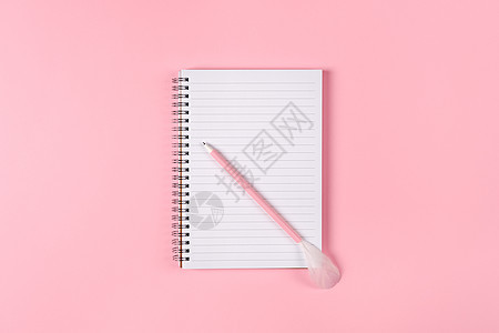 笔记本和粉红笔 上面有粉红色背景的羽毛图片