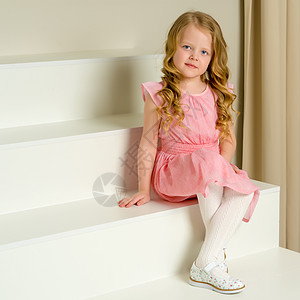 美丽的小女孩坐在白色的楼梯上 笑声教育粉色快乐裙子女性乐趣阁楼孩子工作室享受图片