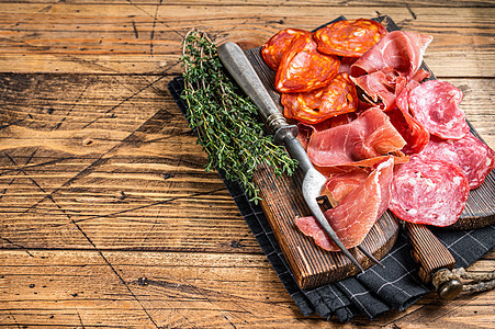 腌肉拼盘作为传统的西班牙小吃 萨拉米香肠 火腿 香肠在木板上 木制的背景 顶视图 复制空间图片