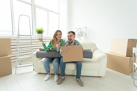 欢快快乐的年轻夫妇迷人的女孩和英俊的男人在搬到新公寓时拿着一个装有东西的盒子和一个装有植物的花盆 乔迁和抵押概念微笑男性女性女士图片