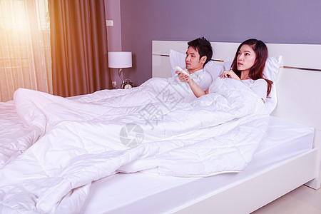 年轻夫妇睡在床上 对卧室空调器进行遥控控制以及温度毯子睡眠护发素说谎羽绒被男人房子夫妻窗户图片
