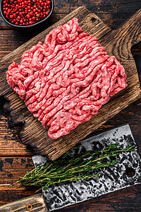 Raw mince牛肉 土肉以及木制切割板上的草药和香料 黑木背景肉馅胡椒羊肉地面猪肉烹饪大理石纹红色食物迷迭香图片