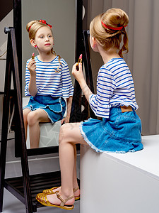 一个小女孩靠近镜子 画着唇唇膏女性眼睛喜悦魅力微笑化妆品童年女儿房间嘴唇图片