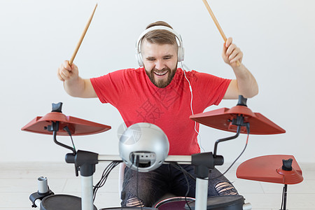 人 音乐和爱好概念     穿红色T恤衫的人在电子鼓架上玩耳机男人仪器盘子喜悦蓝色衬衫工作室娱乐工具背景图片