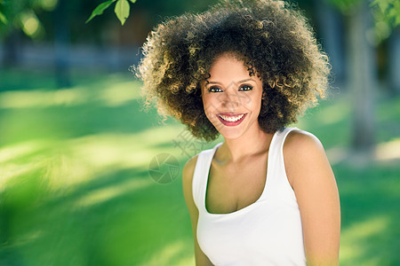 在城市公园笑着带着ffro发型的年轻黑人女子公园快乐女性卷曲头发城市成人爆炸棕色街道图片