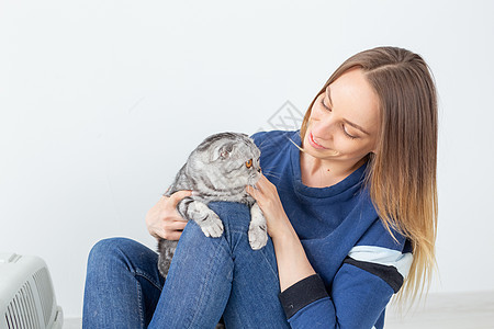 迷人的正派年轻女人手里握着 她美丽的灰色折叠苏格兰猫 坐在地上 在新公寓里 宠物概念动物晶须小猫乐趣尾巴折叠眼睛工作室血统短发图片