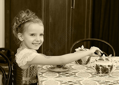 可爱的小女孩在旧桌边喝茶孩子们女性孩子童年裙子婴儿杯子青年食物微笑图片