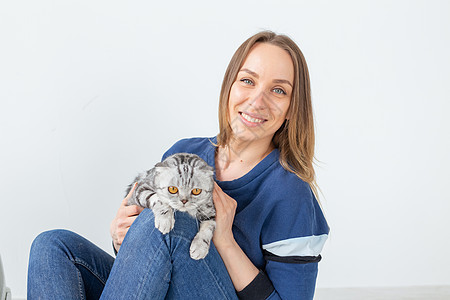 迷人的正派年轻女人手里握着 她美丽的灰色折叠苏格兰猫 坐在地上 在新公寓里 宠物概念哺乳动物虎斑乐趣眼睛伴侣婴儿短发血统猫咪工作图片