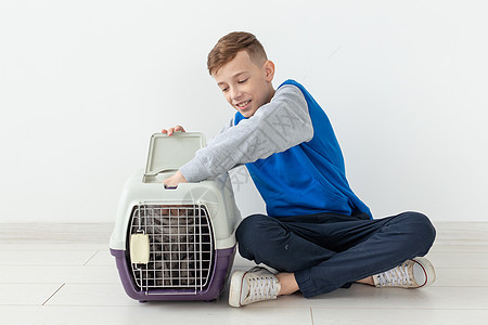 笑笑的男孩拿着一个笼子和一只苏格兰折叠猫坐在他旁边 坐在新公寓的地板上 保护宠物的概念乐趣伴侣哺乳动物婴儿尾巴短发猫咪小猫晶须折图片
